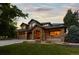 Stunning exterior elevation of stone home with a three car garage and covered front porch at sunset at 5322 Devils Head Cir, Golden, CO 80403