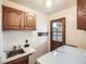 Functional laundry room with sink, wooden cabinets, and exterior door at 6141 W Evans Pl, Lakewood, CO 80227