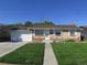 Charming brick home with a well-manicured lawn and an attached garage under a clear blue sky at 6741 Leyden St, Commerce City, CO 80022