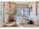 Luxurious bathroom with soaking tub, walk-in glass shower, and a scenic window view at 24860 N Mountain Park Dr, Evergreen, CO 80439