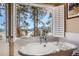 Soaking tub with a view of snow covered mountains through white shuttered windows at 24860 N Mountain Park Dr, Evergreen, CO 80439