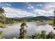 Picturesque lake view surrounded by lush green trees, rolling hills, and mountains in distance at 24860 N Mountain Park Dr, Evergreen, CO 80439