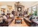 Cozy living room with a stone fireplace, hardwood floors, comfortable couches, and a rustic coffee table for gatherings at 24860 N Mountain Park Dr, Evergreen, CO 80439