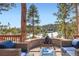 Relax in style on the deck with a cozy firepit and comfortable seating amidst a serene wooded backdrop at 24860 N Mountain Park Dr, Evergreen, CO 80439