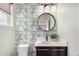 Stylish powder room with patterned wallpaper, a round mirror, modern vanity, and low-flow toilet at 9791 Dunning Cir, Highlands Ranch, CO 80126