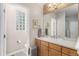 Bright bathroom features a glass block window, large mirror, and a light wood vanity at 11422 W Cooper Ave, Littleton, CO 80127