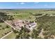 Expansive aerial view of a large estate with various buildings, paddocks, and open fields surrounded by trees at 30886 County Road 17/21, Elizabeth, CO 80107