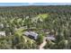 Aerial view showcases a sprawling property surrounded by a dense forest, with a long driveway and outbuildings at 30886 County Road 17/21, Elizabeth, CO 80107
