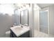 Basement bathroom featuring a single sink vanity, a square mirror, and white tile flooring at 5540 E Jewell Ave, Denver, CO 80222