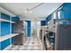 Bright blue laundry room with modern washer/dryer, stainless steel refrigerator, and shelving at 5540 E Jewell Ave, Denver, CO 80222