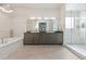 Bright bathroom features a soaking tub, shower with glass door, and double sink vanity at 942 S Fulton St, Denver, CO 80247