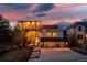 Stunning modern home featuring a sleek design, three-car garage, and beautiful landscaping against a colorful sunset backdrop at 942 S Fulton St, Denver, CO 80247