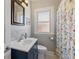Updated bathroom with blue vanity, white sink, and colorful shower curtain at 1454 Utica St, Denver, CO 80204