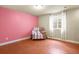 Cozy basement room featuring a pink accent wall, plush chair, and a window with sheer curtains at 297 N Coolidge Way, Aurora, CO 80018