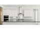 Bright kitchen boasts white cabinets, stainless steel range hood, and gray backsplash at 13805 Emerald Lake St, Parker, CO 80138