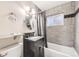 Modern bathroom with gray tile, dark vanity, and shower-tub combo at 2982 S Vrain St, Denver, CO 80236