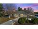 Charming brick home with a well-manicured lawn and mature trees against a colorful sunset sky at 6690 S Sheridan Blvd, Littleton, CO 80123
