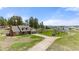 Aerial view showcasing the charming Tudor-style home, barn, outbuildings, and a treehouse on a large grassy lot at 10522 Bayou Gulch Rd, Parker, CO 80134