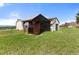 Exterior view of a barn and outbuildings in a grassy field, with a mountain view in the background at 10522 Bayou Gulch Rd, Parker, CO 80134