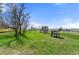 Wide shot of the land featuring a barn and treehouse nestled in a lush, green field under a blue sky at 10522 Bayou Gulch Rd, Parker, CO 80134