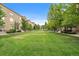 Apartment complex with brick facade, balconies, and large grassy courtyard with mature trees at 190 Roslyn St # 802, Denver, CO 80230