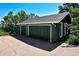 Two car garage with an exterior painted green and set back amongst mature trees at 4380 Sandstone Dr, Monument, CO 80132