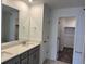Bright bathroom featuring double sinks, white cabinets, and a doorway to the closet at 17115 W 91St Ln, Arvada, CO 80007