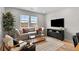 Comfortable living room featuring large windows, a plush sofa, a coffee table, and an entertainment center at 17115 W 91St Ln, Arvada, CO 80007