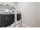 Modern laundry room featuring a white Maytag washer and dryer, shelves, and neutral tile flooring at 17409 Springfield Dr, Parker, CO 80134