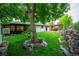 Secluded backyard featuring a lush lawn, mature trees, and an inviting patio with a dining set and rock water feature at 3125 Xenon St, Wheat Ridge, CO 80215