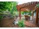 Charming backyard features a dining set under a pergola, lush landscaping, and a decorative rock waterfall feature at 3125 Xenon St, Wheat Ridge, CO 80215