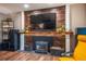 Close-up of the brick fireplace with a wooden mantel, a black firebox, and hardwood-style floors at 3125 Xenon St, Wheat Ridge, CO 80215
