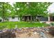 Landscaped front yard with a stone wall, vibrant greenery, and a painted white brick home at 3125 Xenon St, Wheat Ridge, CO 80215