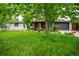 Charming single-story home with a well-manicured lawn, lush trees, and a beautifully painted white brick exterior at 3125 Xenon St, Wheat Ridge, CO 80215