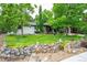 Attractive home featuring a stone retaining wall, lush landscaping, a well-maintained lawn, and white painted brick at 3125 Xenon St, Wheat Ridge, CO 80215