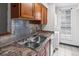 Close-up of kitchen sink with tiled backsplash and laundry appliances nearby at 865 S Quebec St # 101B, Denver, CO 80247