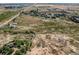 Open aerial view of vast land with houses, trees, a creek and road at 3550 E 160Th Ave, Thornton, CO 80602
