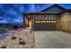 Nighttime view of home's stone exterior with garage, featuring a walkway leading to the front door at 3703 New Haven Cir, Castle Rock, CO 80109