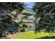 Multi-story condo building featuring green balconies, surrounded by mature trees and a well-manicured lawn at 2150 S Vaughn Way # 302D, Aurora, CO 80014