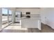 Modern kitchen features an island, stainless steel appliances, white cabinets, and natural light from the sliding glass door at 16622 E 109Th Ave, Commerce City, CO 80022