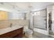 Bright bathroom with a modern vanity, toilet, shower/tub, and neutral tile at 8 Lindenwood Dr, Littleton, CO 80120
