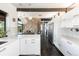 Modern kitchen with white cabinets, stainless steel appliances, and views of a stunning stone fireplace feature at 8 Lindenwood Dr, Littleton, CO 80120