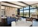 Bright living room featuring a stone fireplace, dark wood floors and beams, and a wall of windows with outdoor views at 8 Lindenwood Dr, Littleton, CO 80120