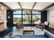 An airy living room with a stone fireplace, expansive windows and a view of trees and a deck at 8 Lindenwood Dr, Littleton, CO 80120