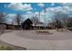 Community clubhouse with flags, a roundabout, and surrounding bare trees at 19414 E Mann Creek Dr # C, Parker, CO 80134