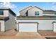 Exterior elevation of a grey two story townhome with a large white garage door and gravel landscaping at 1419 Great Western Dr, Longmont, CO 80501