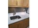 Close-up of a kitchen sink featuring marble-style countertops, undermount lighting and wood cabinets at 9105 E Lehigh Ave # 105, Denver, CO 80237