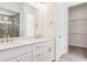 Bathroom with a double sink vanity, sleek white cabinets, and access to the walk-in closet and glass enclosed shower at 8245 Cokedale Cir, Littleton, CO 80125