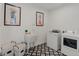 Modern laundry room with patterned tile flooring, a utility sink, and a front loading washer and dryer at 953 Compass Dr, Erie, CO 80516