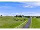 Expansive lot with white fencing, a long driveway and a two-story home centered in the background at 46093 Bristlecone Ct, Parker, CO 80138